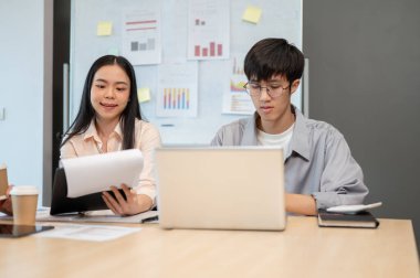 Güzel bir Asyalı iş kadını, erkek arkadaşı toplantıda dizüstü bilgisayarı üzerinde çalışırken ekibine proje detaylarını anlatıyor..