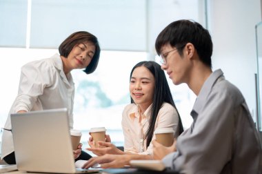 Bir grup yetenekli ve profesyonel Asyalı iş adamı toplantıda, yeni bir proje hakkında konuşuyor ve beyin fırtınası yapıyorlar, birlikte dizüstü bilgisayar ekranına bakıyorlar. Takım çalışması konsepti