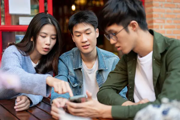 Group of young Asian friends hang out on the weekend at a restaurant in the city together, enjoying talking about random topics and having a good time together. Friendship and lifestyle concepts