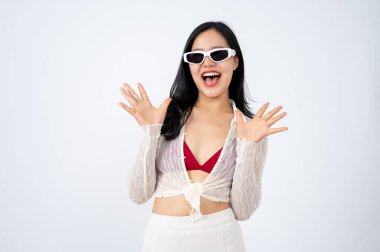 Yaz kıyafetleri ve güneş gözlüğü takmış pozitif bir Asyalı kadın kameraya sevimli bir poz veriyor ve gülümsüyor, izole beyaz arka plan. Yaz tatili, plaj tatili