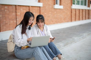İki Asya okulunun en iyi iki arkadaşı binanın dışında dizüstü bilgisayar kullanarak bir proje üzerinde konuşuyor ve çalışıyorlar. Eğitim ve arkadaşlık kavramları