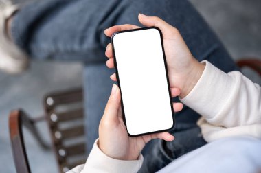 Açık havada otururken akıllı telefonunu kullanan kotlu bir kadının yakın plan görüntüsü. Beyaz ekran akıllı telefon modeli.