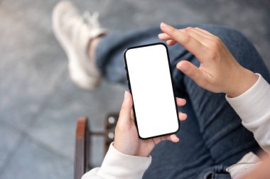 Açık havada otururken akıllı telefonunu kullanan kotlu bir kadının yakın plan görüntüsü. Beyaz ekran akıllı telefon modeli.