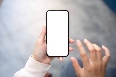 Günlük kıyafet giymiş bir kadın dışarıda otururken, blog okurken ya da sosyal medyada kayarken akıllı telefonunu kullanıyor. Akıllı telefon beyaz ekran maketi. İnsanlar ve teknoloji kavramları