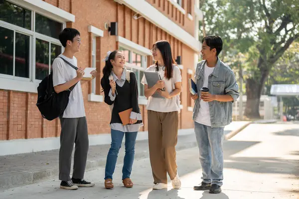 Group of diverse happy Asian college students are enjoying talking, sharing ideas, chatting after classes on a footpath on their campus. Friendship and university life concepts