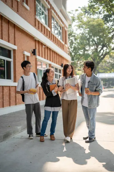 Group of diverse happy Asian college students are enjoying talking, sharing ideas, chatting after classes on a footpath on their campus. Friendship and university life concepts