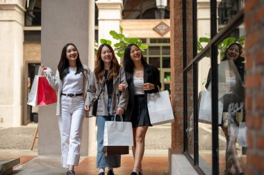 Bir grup neşeli ve çekici Asyalı genç kız alışveriş günlerinin tadını çıkarıyor, alışveriş torbalarıyla yürüyor, birlikte eğleniyorlar. Yaşam tarzı ve arkadaşlık kavramları