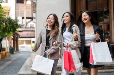 Bir grup eğlenceli, çekici Asyalı genç kız arkadaş yurt dışı gezileri sırasında şehirde alışveriş yapıyorlar. Boş zaman, yaşam tarzı, moda, şehir hayatı.