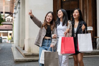 Bir grup eğlenceli, çekici Asyalı genç kız arkadaş yurt dışı gezileri sırasında şehirde alışveriş yapıyorlar. Boş zaman, yaşam tarzı, moda, şehir hayatı.
