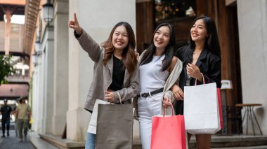 Bir grup eğlenceli, çekici Asyalı genç kız arkadaş yurt dışı gezileri sırasında şehirde alışveriş yapıyorlar. Boş zaman, yaşam tarzı, moda, şehir hayatı.