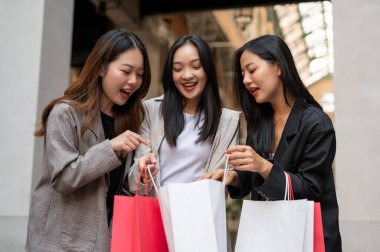 Neşeli ve eğlenceli Asyalı genç kız arkadaşlar alışveriş günlerinin tadını çıkarıyorlar, alışveriş çantalarını taşıyorlar. Tüketim, alışveriş, moda, şehir hayatı