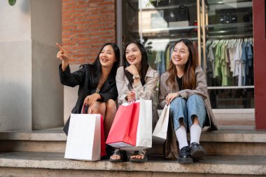 Bir grup mutlu ve güzel Asyalı bayan arkadaş şehirde alışveriş günlerinin tadını çıkardıktan sonra merdivenlerde dinleniyorlar. Arkadaşlık, şehir hayatı, yaşam tarzı.