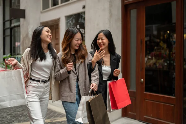 Bir grup güzel ve neşeli Asyalı genç kız alışveriş torbalarıyla yürüyor, gülüyorlar, hafta sonları alışveriş caddesinde birlikte alışveriş yapıyorlar. Moda ve yaşam tarzı kavramları