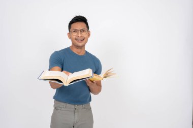 Sıradan giysiler içindeki cahil, kuşkulu Asyalı bir adam izole edilmiş beyaz bir stüdyo arka planında dururken kitaplarla poz veriyor. Halk ve eğitim kavramları