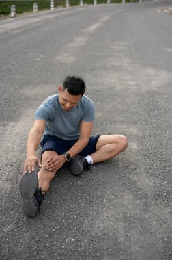 Spor giyimli mutlu ve güçlü bir Asyalı adam spor yapmadan önce ya da egzersizden sonra ısınmak için vücudunu dışarıda geriyor. Koşucu, koşucu, atlet