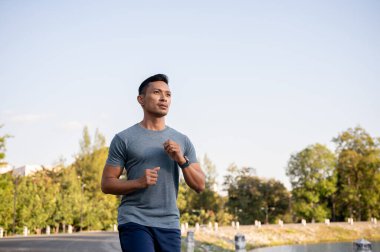 Formda ve güçlü bir Asyalı spor giyimli adam sabahın köründe sokakta koşuyor. egzersiz, egzersiz, maraton