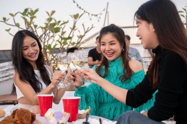 Bir grup çekici Asyalı genç bayan arkadaş şampanya içiyor, kutlama yapıyor, eğleniyor ve çatıdaki bir barda parti yapıyorlar. Şehir hayatı, kızlar gecesi, arkadaşlık, yaşam tarzı.