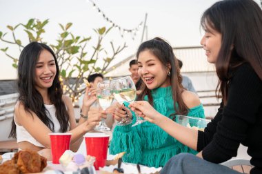 Bir grup çekici Asyalı genç bayan arkadaş şampanya içiyor, kutlama yapıyor, eğleniyor ve çatıdaki bir barda parti yapıyorlar. Şehir hayatı, kızlar gecesi, arkadaşlık, yaşam tarzı.