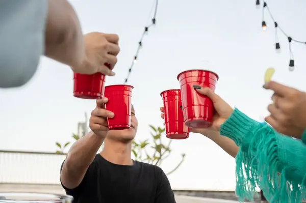 Group of friends partying on a rooftop bar and toasting drinks. Happy young people with beers. celebration and nightlife concept. close-up image