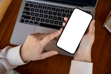 Çalışma masasında akıllı telefonunu kullanan bir kadının en iyi görüntüsü. Bir kadının elinde beyaz ekran akıllı telefon modeli var. İnsanlar ve teknoloji kavramları