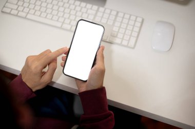 Ofis masasında akıllı telefonunu kullanan bir adamın en iyi görüntüsü. Beyaz ekran akıllı telefon modeli, bir erkeğin elinde. İnsanlar ve teknoloji kavramları