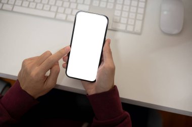 Ofis masasında akıllı telefonunu kullanan bir adamın en iyi görüntüsü. Beyaz ekran akıllı telefon modeli, bir erkeğin elinde. İnsanlar ve teknoloji kavramları