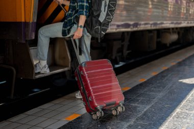 Sırt çantası ve bavulu olan bir turistin kesilmiş görüntüsü tren istasyonunda trene biniyor. Tek başına seyahat, yaz tatili, seyahat.