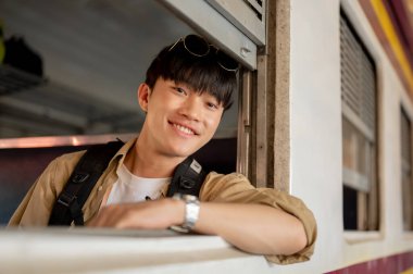 Mutlu, yakışıklı genç Asyalı bir gezgin trende, pencerenin kenarında oturuyor ve trenle bir yerlere gidiyor. İnsanlar ve ulaşım kavramları