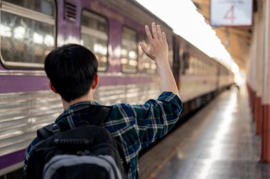 Arka planda genç bir Asyalı adamın el sallayıp tren istasyonundaki birine veda edişinin görüntüsü var. İnsanlar ve ulaşım kavramları