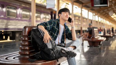 Yakışıklı genç bir Asyalı, tren istasyonunda onu beklerken arkadaşıyla telefonda konuşuyor, platformdaki bir bankta oturuyor. Halk ve toplu taşıma kavramları