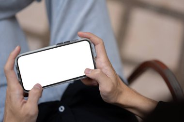 Akıllı telefonunu kullanan, oyun oynayan ya da dışarıda otururken online video izleyen bir adamın yakın plan görüntüsü. Akıllı telefon maketi. İnsanlar ve teknoloji kavramları