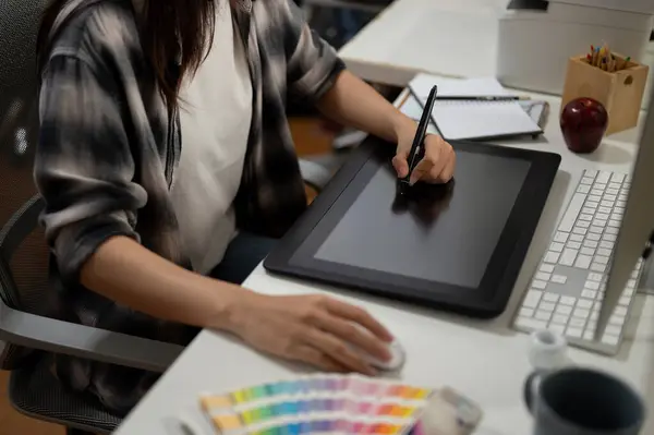 Close-up image of a professional female graphic designer illustrator artist working in the office, drawing something on a graphic tablet.