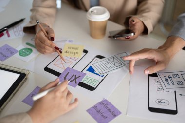 Yeni mobil uygulama için grafik tasarımcı ekibi ve çeşitli prototipli bir toplantı masasının yakın plan görüntüsü. UI UX kavramı