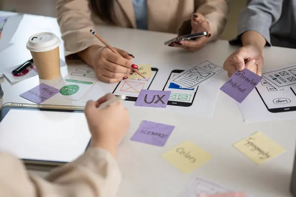 Close-up image of a meeting table with a graphic designer team and various prototype for a new mobile application. UI UX concept