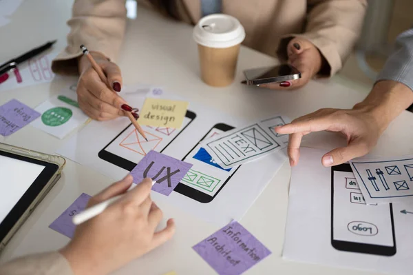 Close-up image of a meeting table with a graphic designer team and various prototype for a new mobile application. UI UX concept