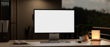 Geceleri modern bir karanlık ofis, beyaz ekran bilgisayar modeli, masa lambası ve aksesuarları olan. 3d görüntüleme, 3d illüstrasyon