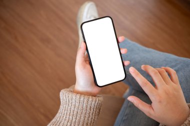 Kapalı alanda akıllı telefonunu kullanan örgü kazaklı bir kadının yakın plan görüntüsü. Grafik reklamlarınızı göstermek için beyaz ekran akıllı telefon modeli. insanlar ve teknoloji kavramları