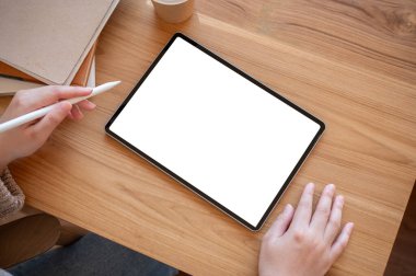 Masasında dijital tablet kullanan bir kadının en üst görüntüsü. Tahta bir masada beyaz ekran dijital tablet modeli. insanlar ve teknoloji kavramları