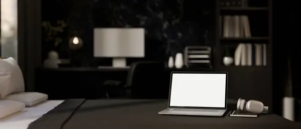 A white-screen laptop computer, a book, and a headphone on a bed in a modern black bedroom. home workplace, remote work, work from home. 3d render, 3d illustration
