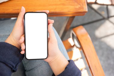 Bir kafede dinlenirken akıllı telefonunu kullanan bir kadının yakın plan fotoğrafı. Bir kadının elindeki akıllı telefon beyaz ekran maketi. sohbet, sosyal medya, mesajlar, online alışveriş, mobil uygulamalar