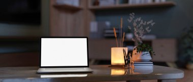 Akşamları, karanlık bir oturma odasındaki mermer bir kahve masasının üzerinde beyaz ekran dizüstü bilgisayar olan bir ev çalışma alanı. Görüntüyü yaklaştır. 3d görüntüleme, 3d illüstrasyon