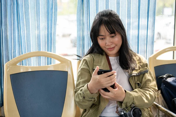 Halka açık bir otobüste arkadaşlarıyla sohbet eden mutlu, genç bir Asyalı kadın. modern şehir hayatı konsepti