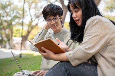 İki genç Asyalı üniversite öğrencisi fikirlerini paylaşıyor, sınava hazırlanıyor veya üniversite parkında birlikte bir proje üzerinde çalışıyorlar..