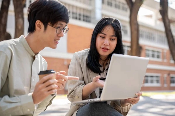 Zeki bir Asyalı kız üniversite öğrencisi üniversite parkında birlikte otururken bilgisayarında bir şeyi açıklarken arkadaşının sınav için hazırlanmasına yardım ediyor..