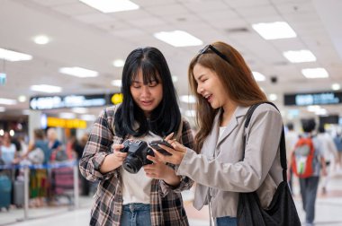İki neşeli Asyalı bayan arkadaş gezginler havaalanında yürürken konuşuyor, birlikte seyahat ediyorlar. insanlar ve ulaşım kavramları