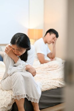 Pijamalı mutsuz, üzgün bir Asyalı kadın kocasıyla tartıştıktan sonra yüzünü kapatıp ağlıyor. evlilik sorunları, ayrılık, kavga, sağlıksız ilişki, boşanma