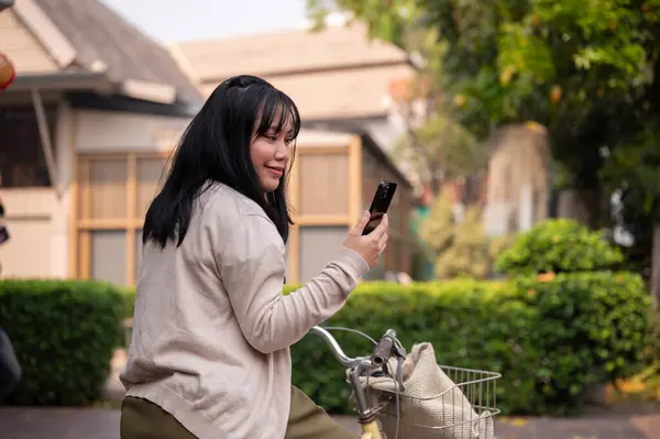 Güzel Mutlu Bir Asyalı Kadın Şehirde Bisiklet Sürerken Akıllı Telefonunu — Stok fotoğraf