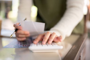 Hesap makinesi kullanan, makbuzları inceleyen ve dükkanının mali durumunu yöneten bir kadın küçük işletme sahibinin yakın plan fotoğrafı. insanlar ve finansal kavramlar