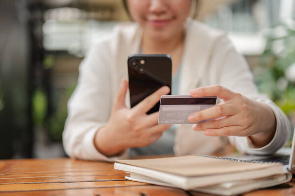A cropped image of a woman in casual wear sitting at an outdoor space, using a mobile banking app or registering her credit card on a shopping website. online payment, money transferring, cashless