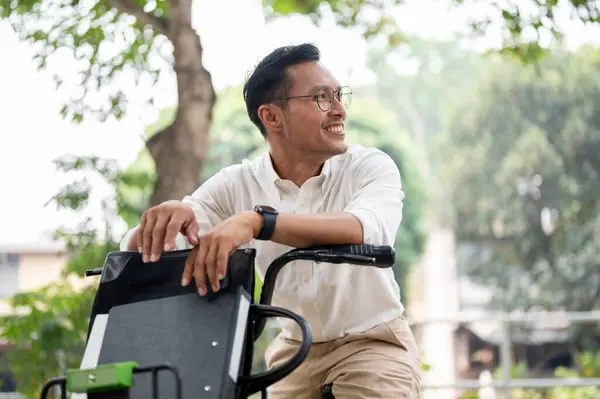A handsome, happy Asian millennial businessman is on a bike in the park, riding a bike to work in the morning. businesspeople and transportation concepts